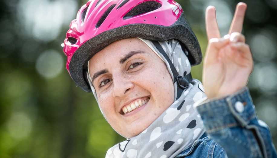 Junge Frau mit Fahrradhelm, die das Victory-Zeichen macht